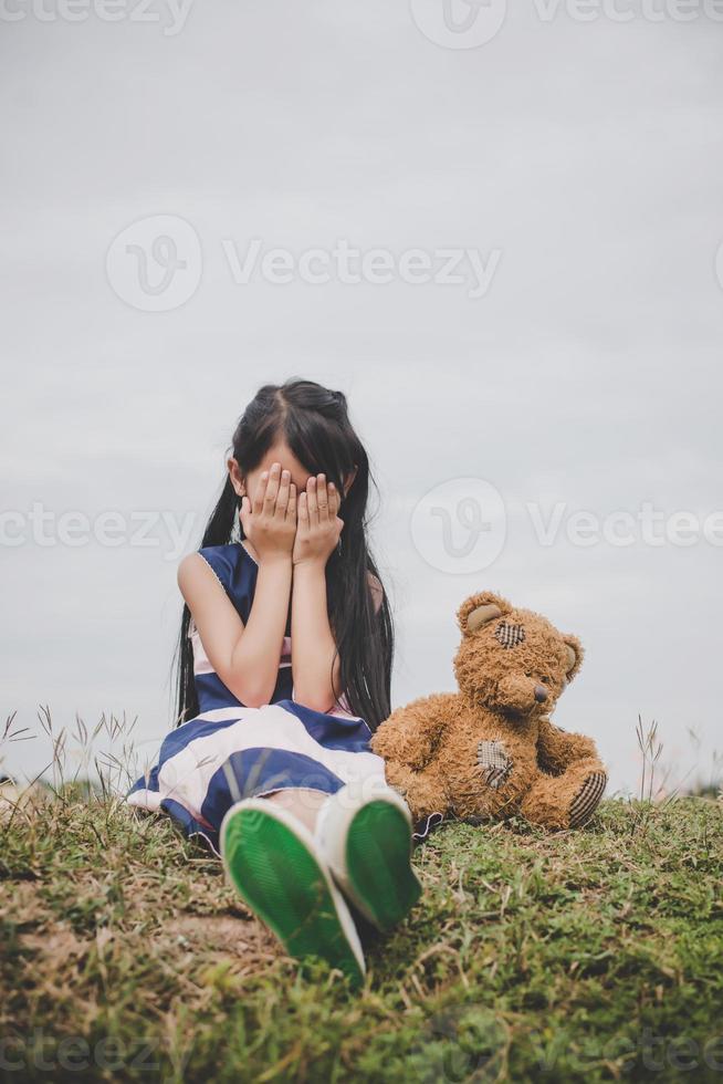 kleines Mädchen sitzt mit ihrem Bären verärgert foto