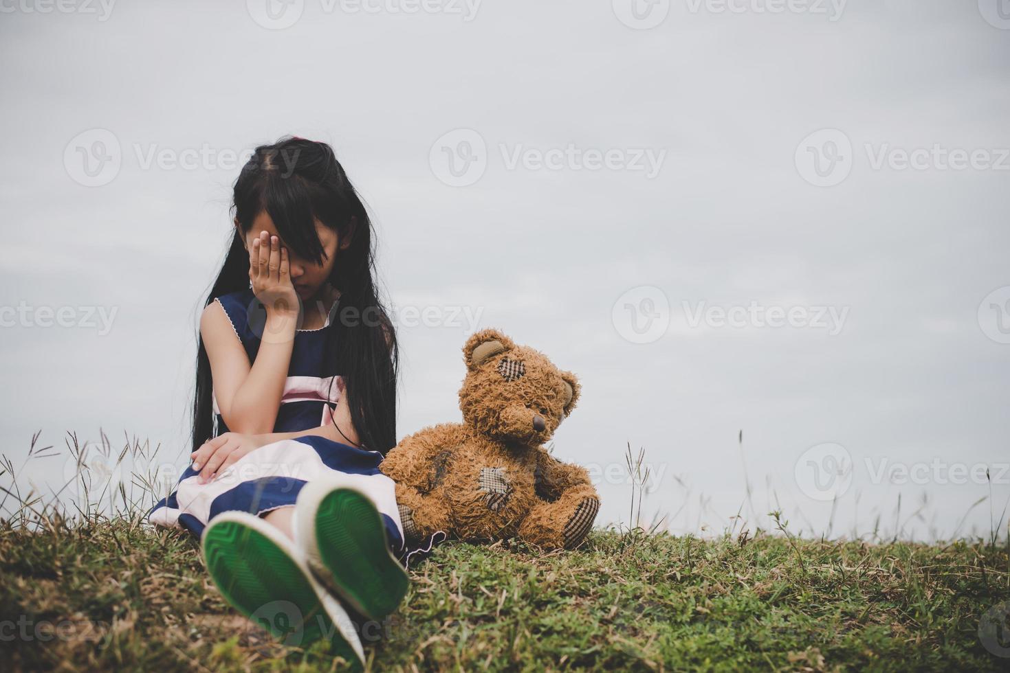 kleines Mädchen sitzt mit ihrem Bären verärgert foto