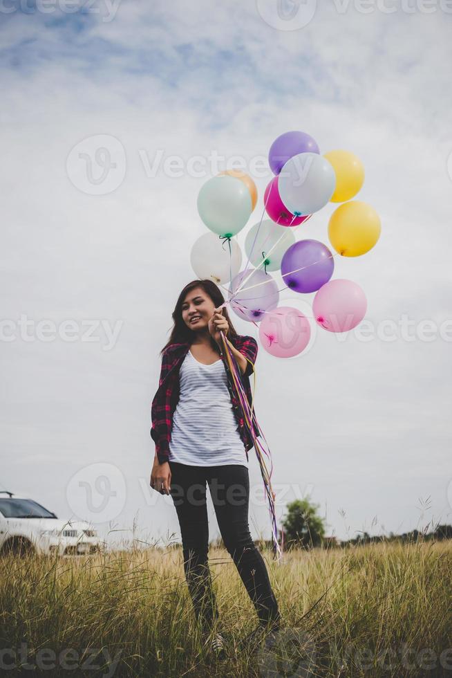 schöne junge Hipsterfrau, die bunte Luftballons draußen hält foto