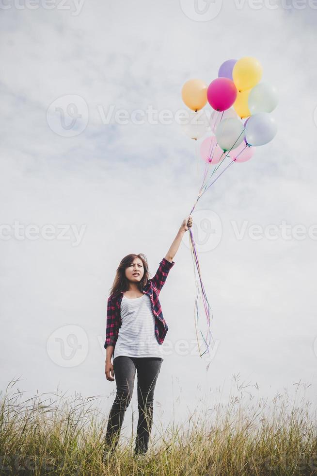 schöne junge Hipsterfrau, die bunte Luftballons draußen hält foto