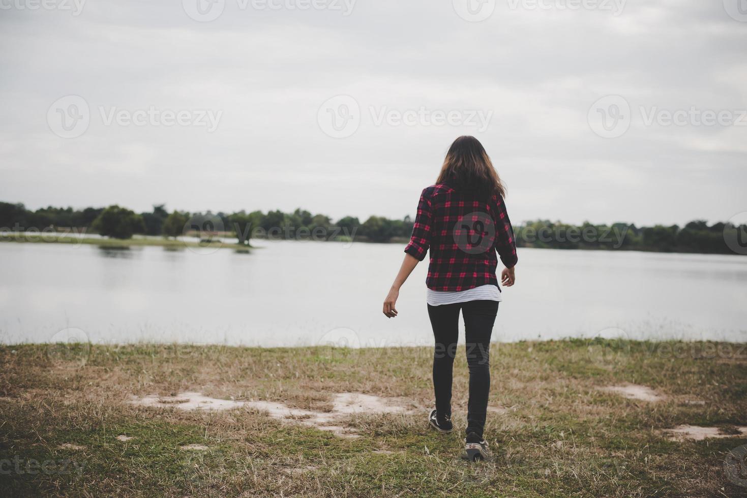 glückliche Hipsterfrau, die zum See geht foto