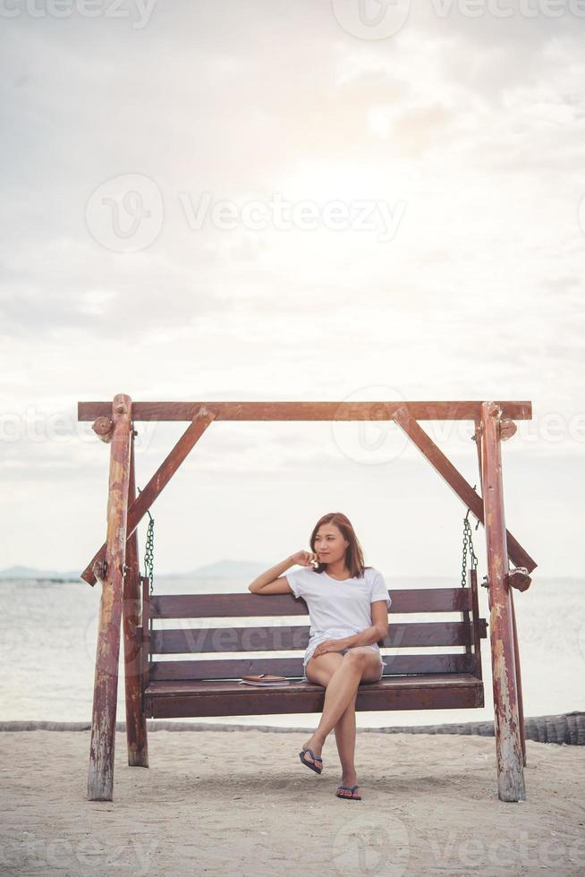 schöne Frau, die sich auf einer Schaukel am Strand ausdehnt foto