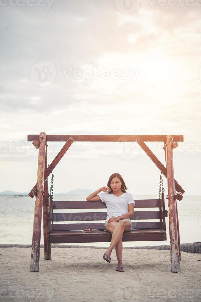 schöne Frau, die sich auf einer Schaukel am Strand ausdehnt foto