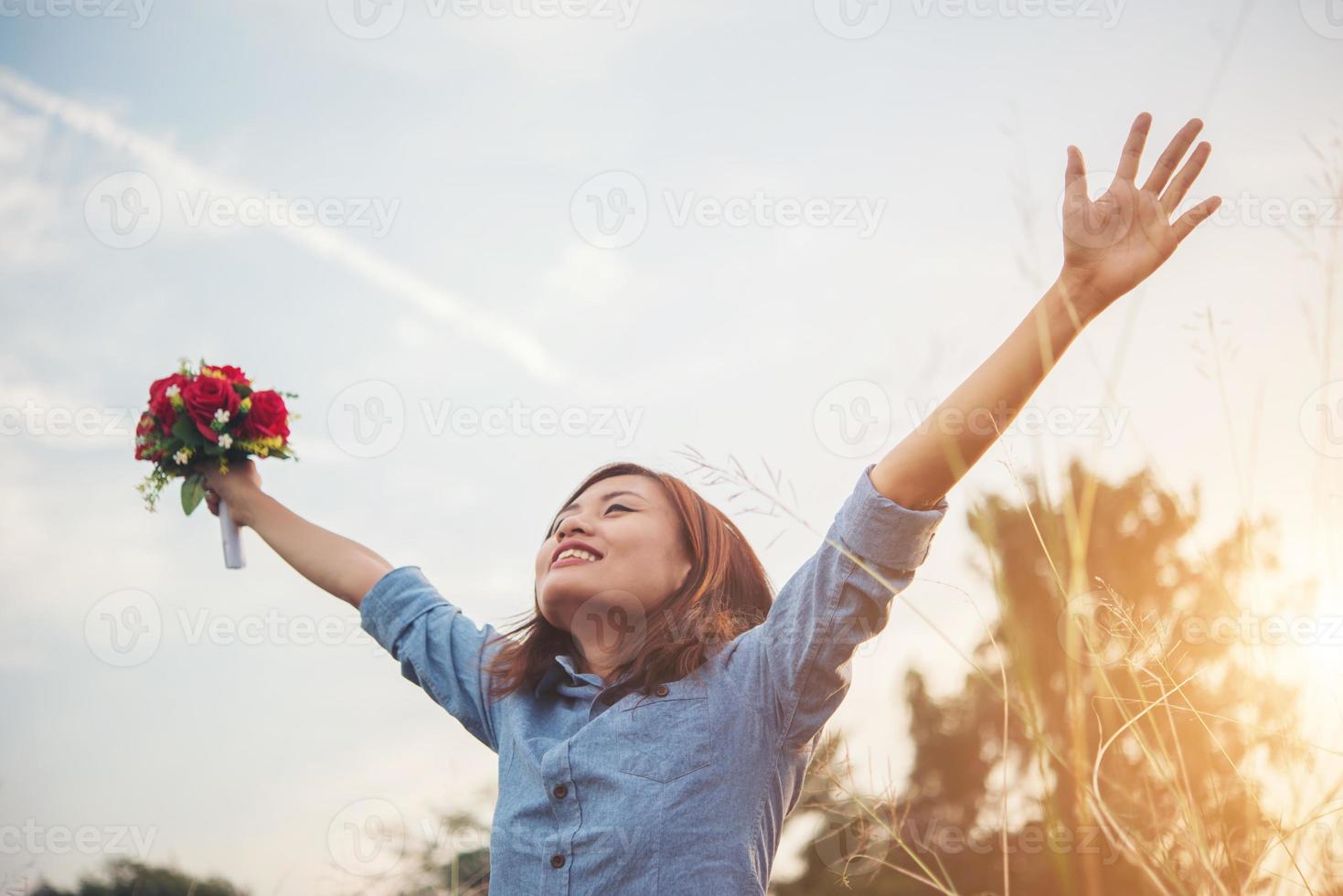 schöne Frau Hipster hebt ihre Arme in der Luft mit Blumenstrauß foto