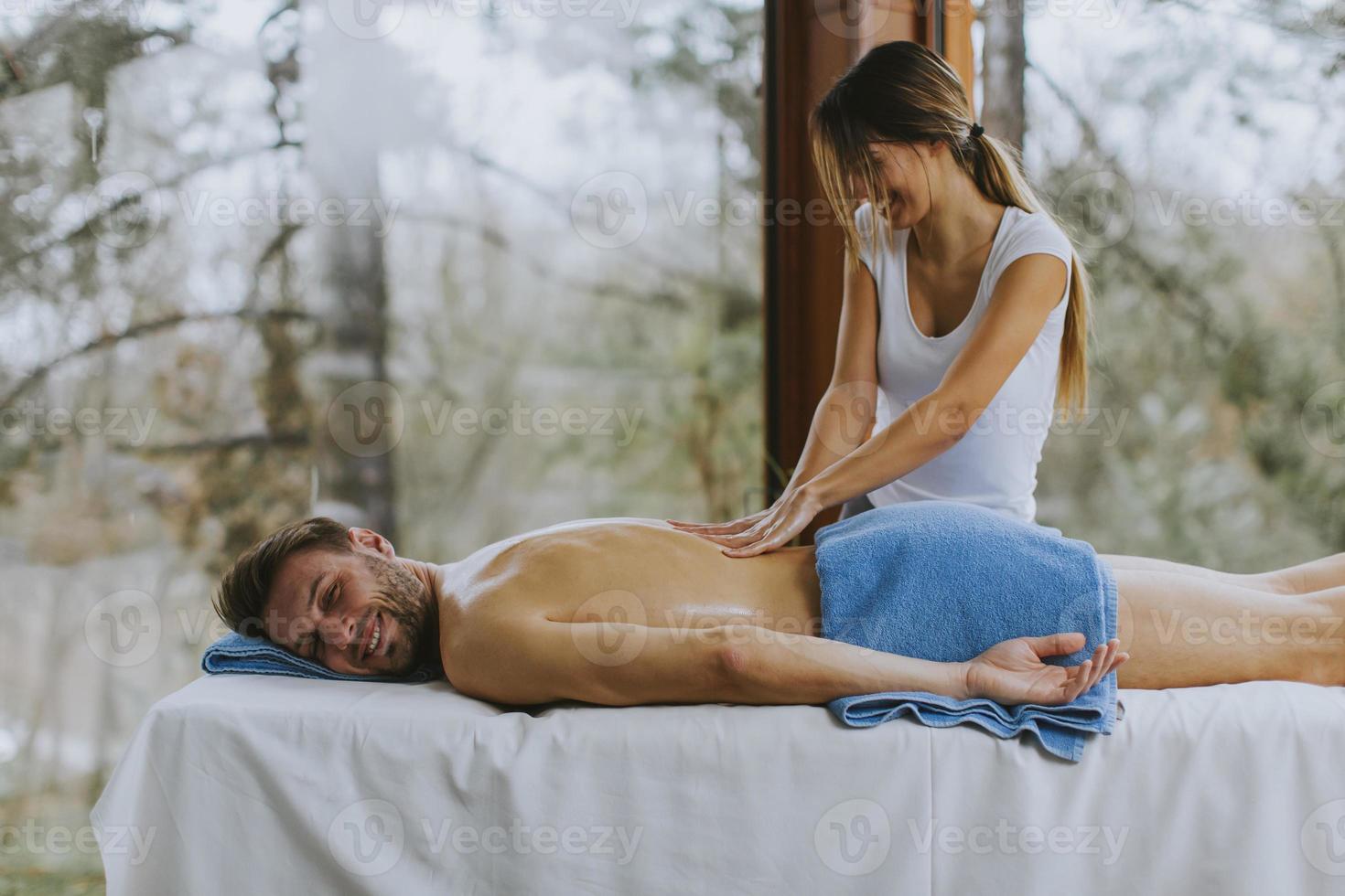 schöner junger Mann, der während der Wintersaison im Spa-Salon liegt und Rückenmassage hat foto