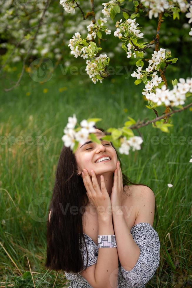 das Mädchen ist Stehen unter ein Baum mit ihr Augen geschlossen. Weiß Blütenblätter sind fallen auf das Gesicht foto