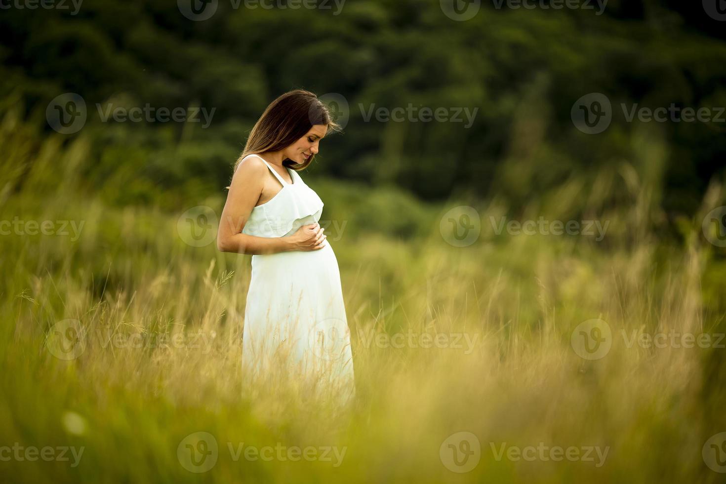 junge schwangere Frau, die draußen in der Natur entspannt foto