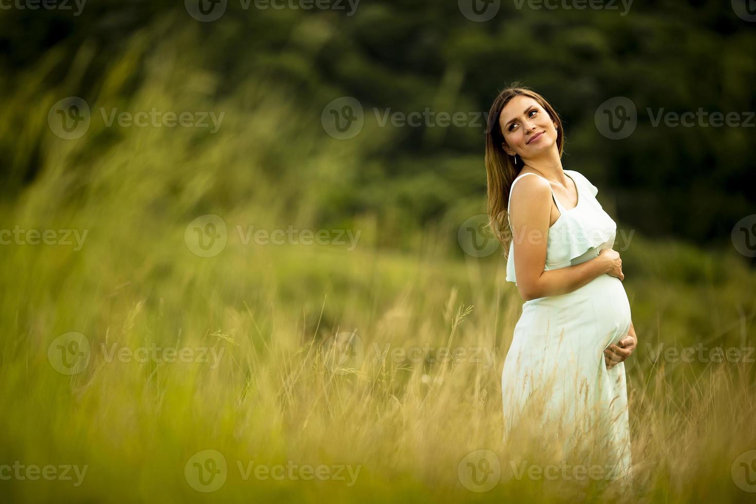 junge schwangere Frau, die draußen in der Natur entspannt foto