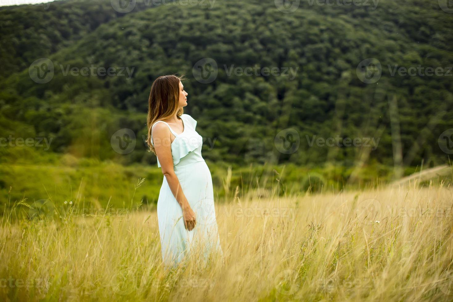 junge schwangere Frau, die draußen in der Natur entspannt foto