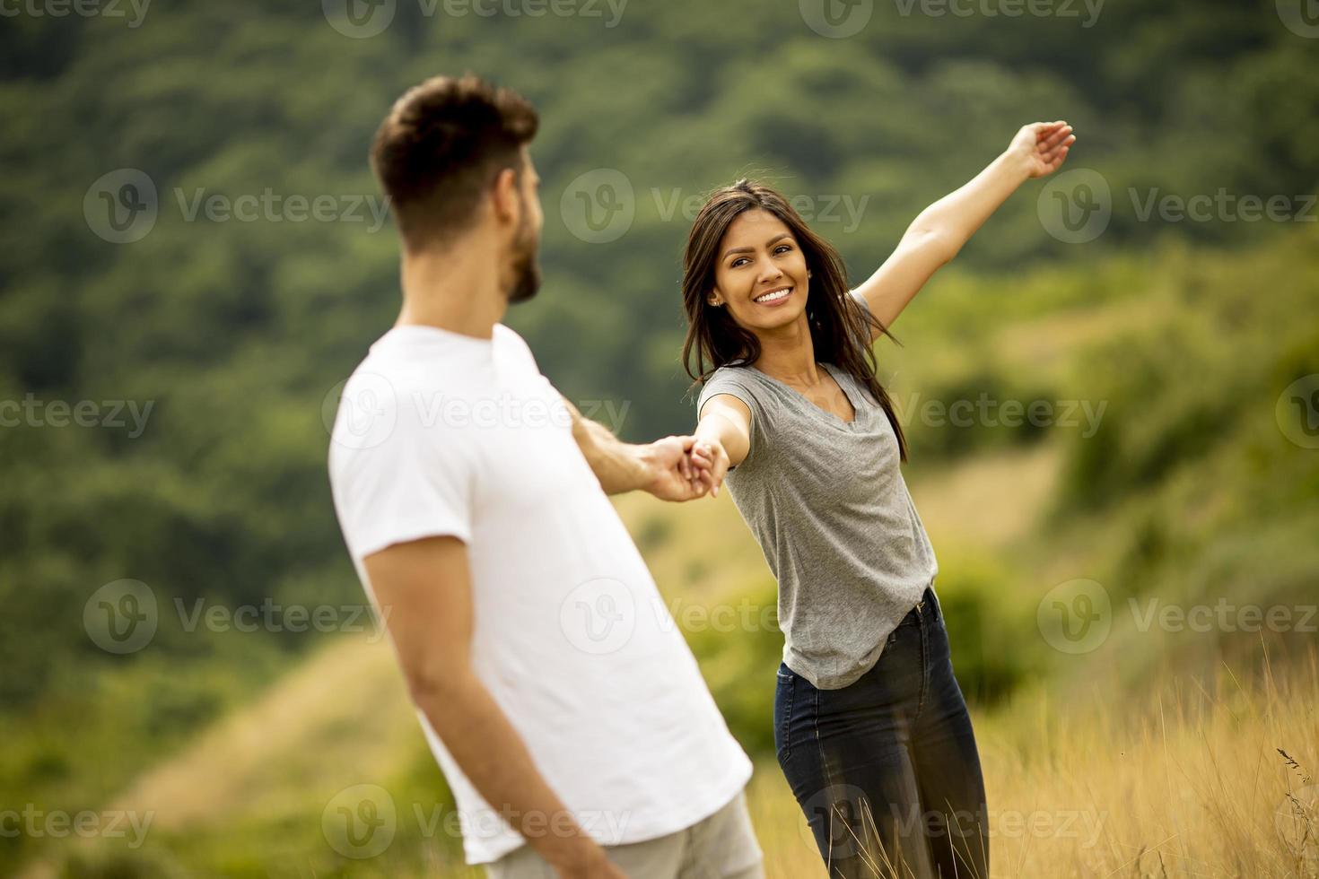 glückliches junges Paar in der Liebe, die durch Grasfläche geht foto