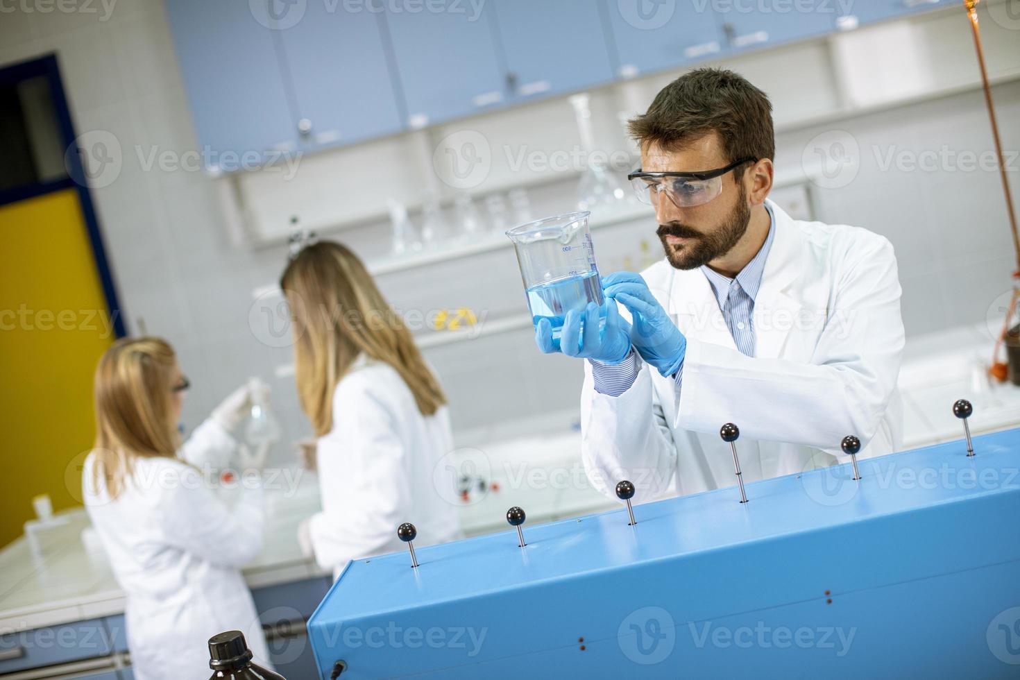 junge Forscher arbeiten mit blauer Flüssigkeit in Laborglas foto