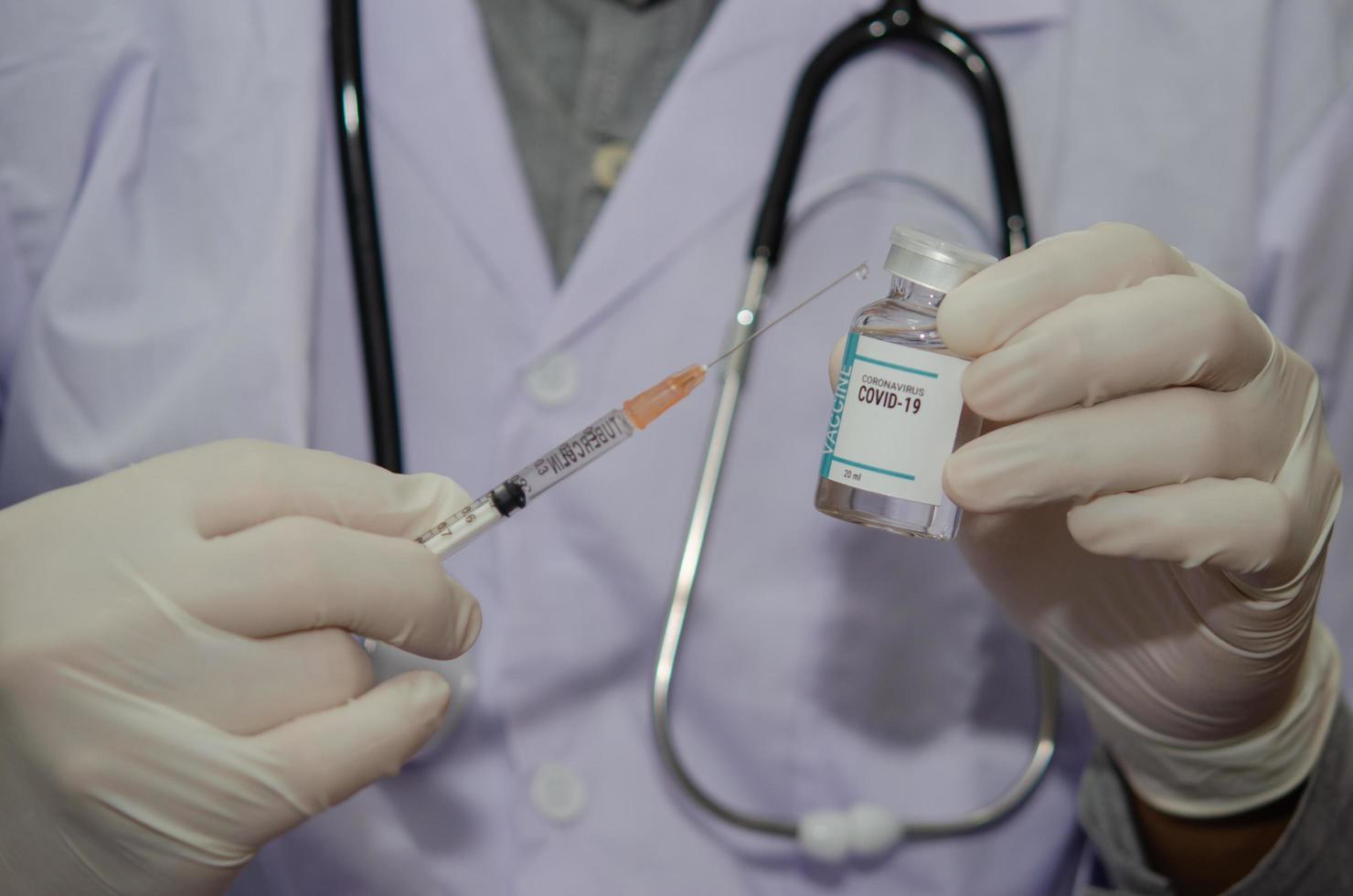 ein männlicher Arzt, der eine Flasche des Covid-19- oder des Coronavirus-Impfstoffs in der Hand hält foto