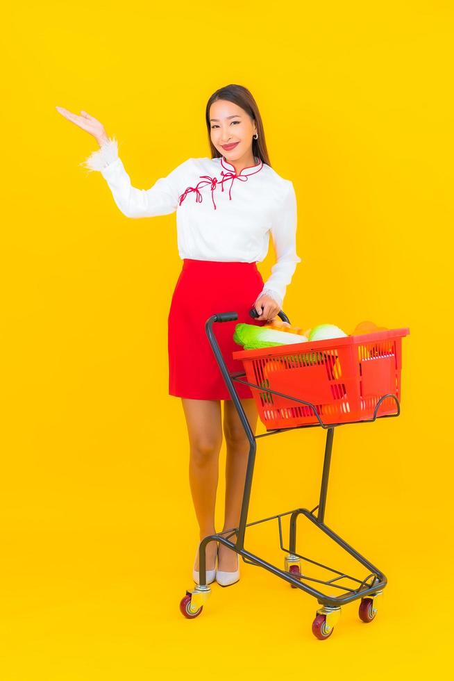 schöne junge asiatische Frau mit Einkaufswagen foto