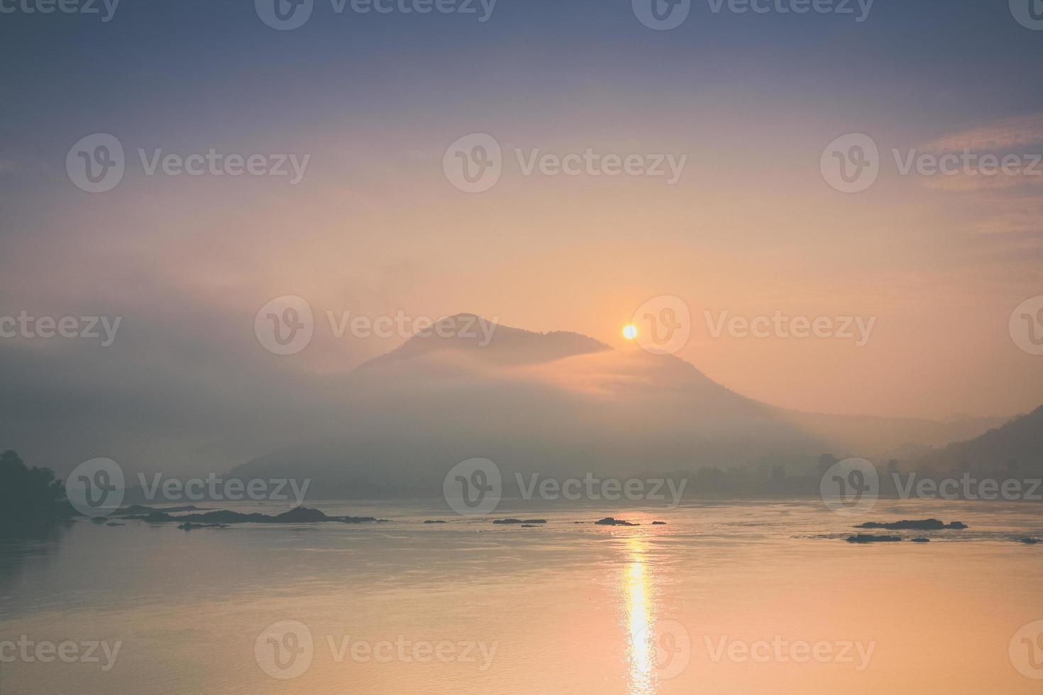 Sonnenaufgang über nebligen Bergen und Wasser foto