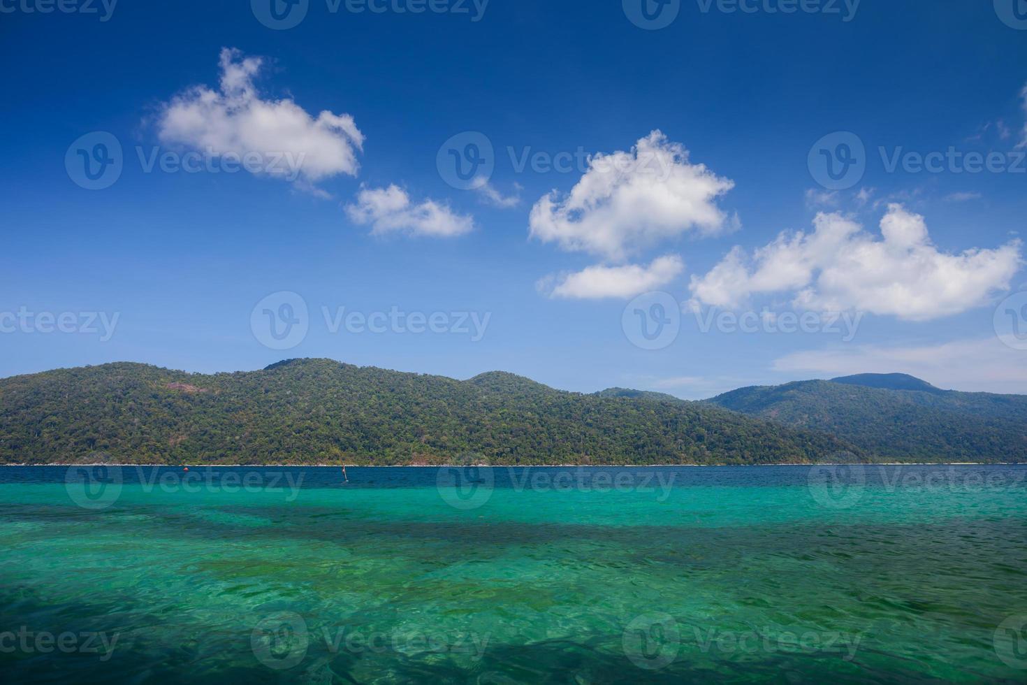 blaues Wasser mit Bergen und flauschigen weißen Wolken foto