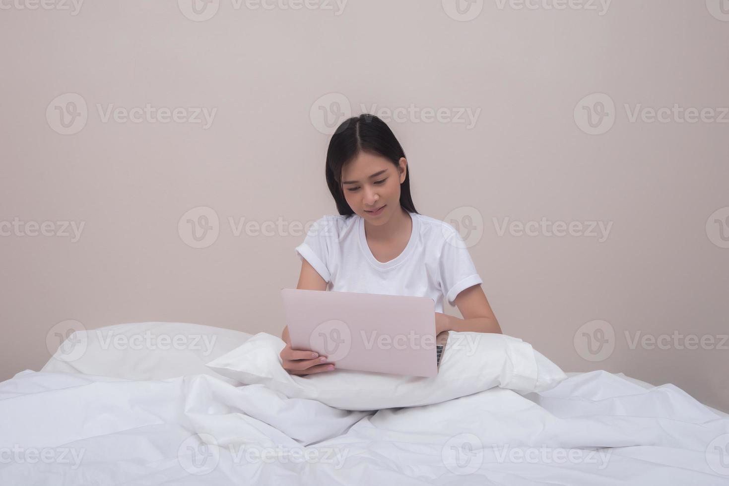 glückliche Frau mit Laptop auf dem Bett zu Hause am Morgen foto