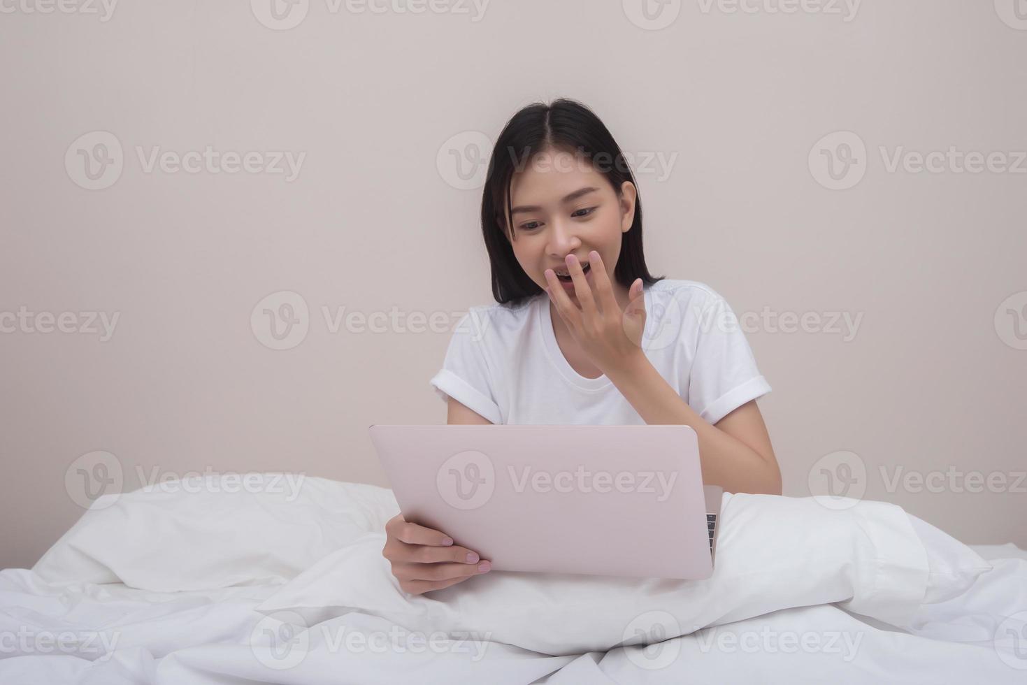 glückliche Frau mit Laptop auf dem Bett zu Hause am Morgen foto