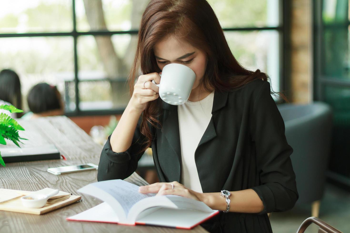 asiatische Geschäftsfrau, die Kaffee liest und trinkt foto