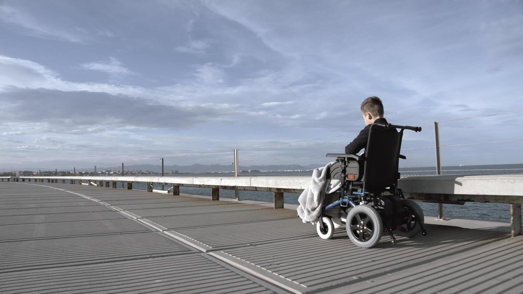Junge im Rollstuhl am Strand foto