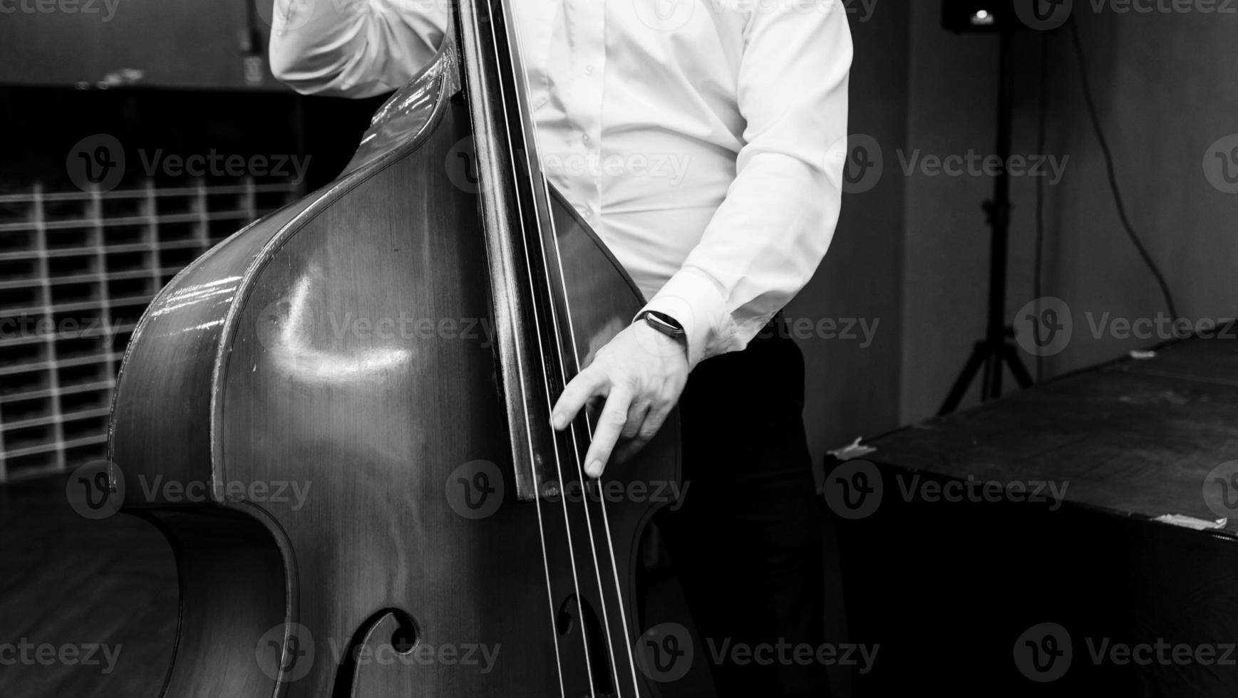 Musiker im ein Weiß Hemd Theaterstücke das doppelt Bass foto