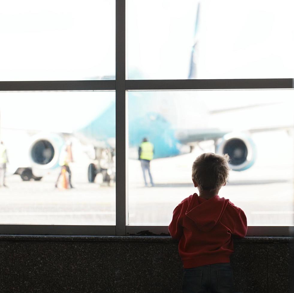 Junge, der Flugzeug am Flughafen betrachtet foto