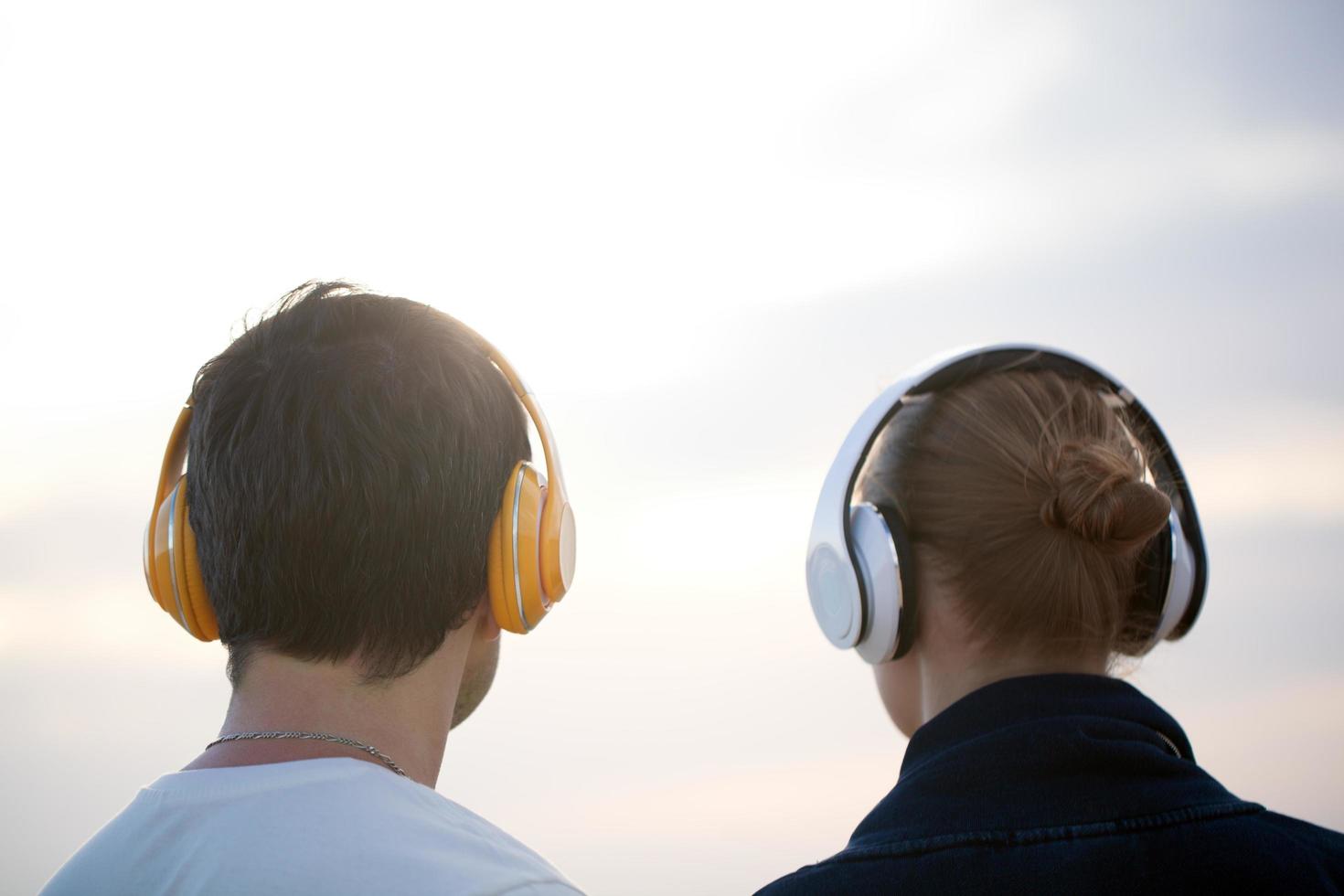 junge Leute in Kopfhörern, die draußen Musik genießen foto