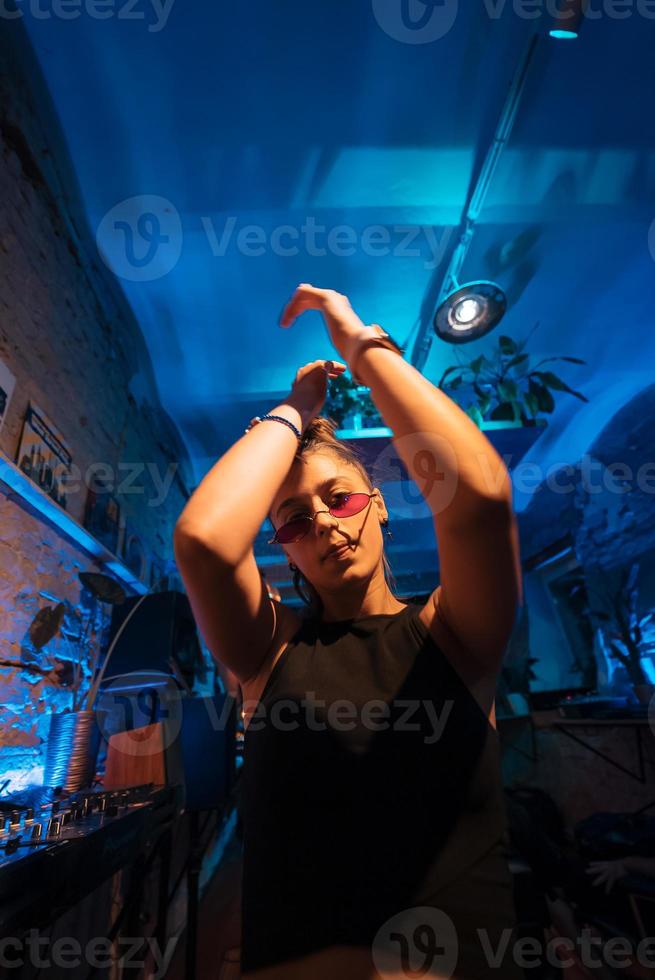 schöne dj-frau, die in einem kleinen club zu techno tanzt foto