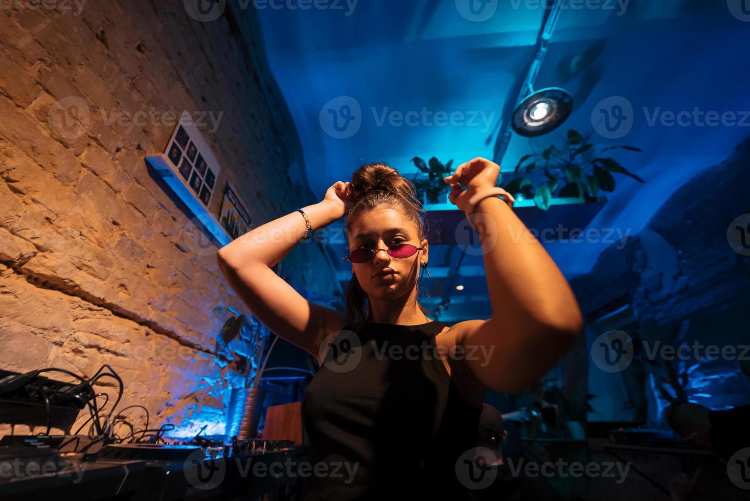 schöne dj-frau, die in einem kleinen club zu techno tanzt foto