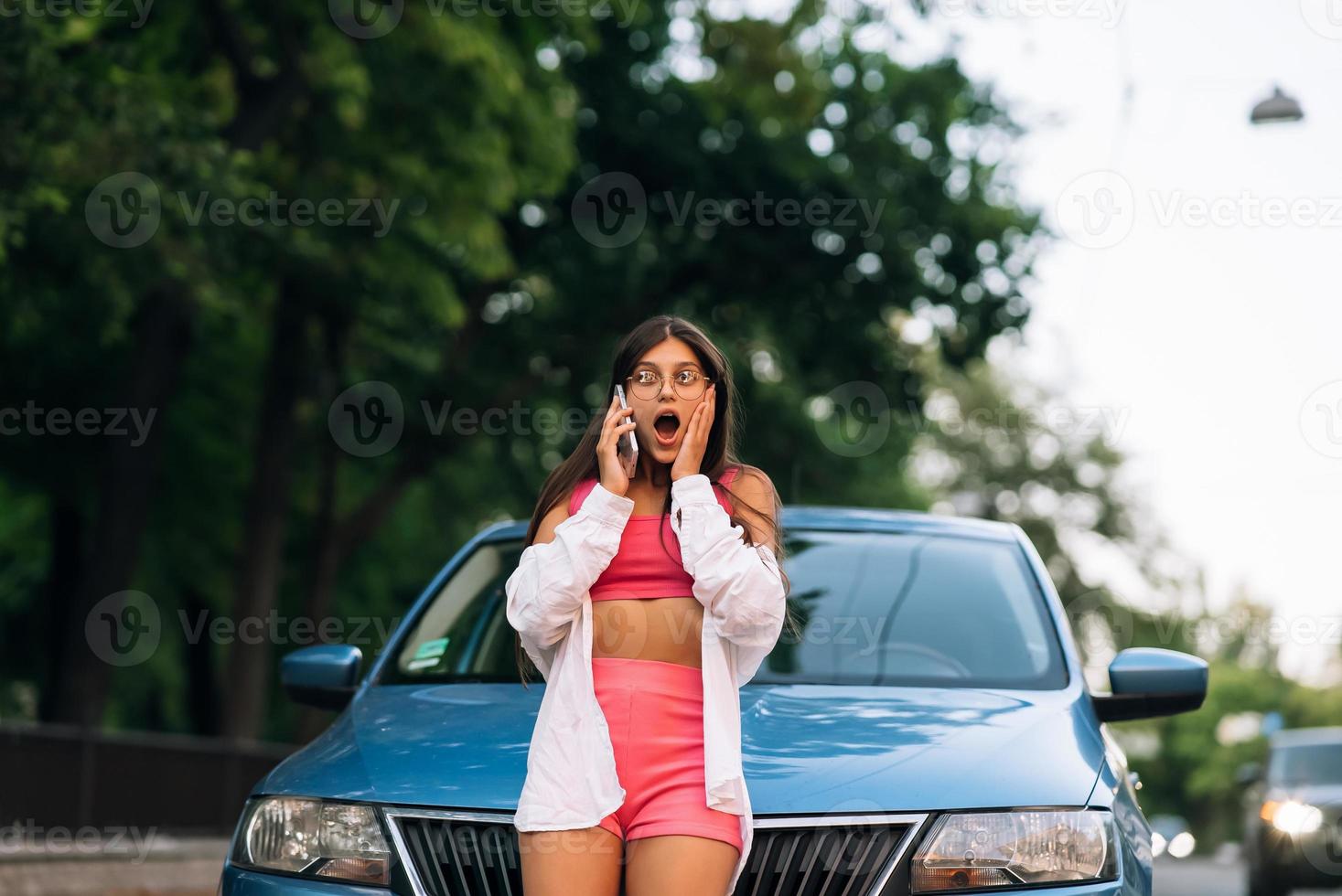 Frau telefoniert in der Nähe des Autos auf der Straße foto