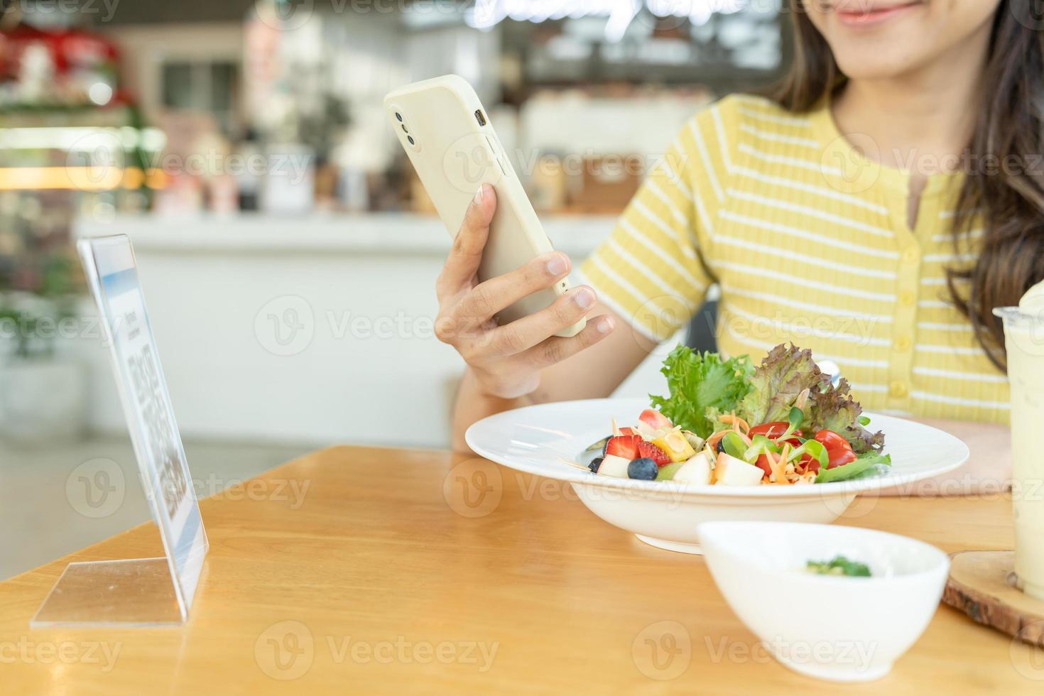 frau verwendet smartphone, um qr-code zu scannen, um im caférestaurant mit einer digitalen zahlung ohne bargeld zu bezahlen. Menü wählen und bestellen Rabatt kumulieren. E-Geldbörse, Technologie, online bezahlen, Kreditkarte, Bank-App. foto