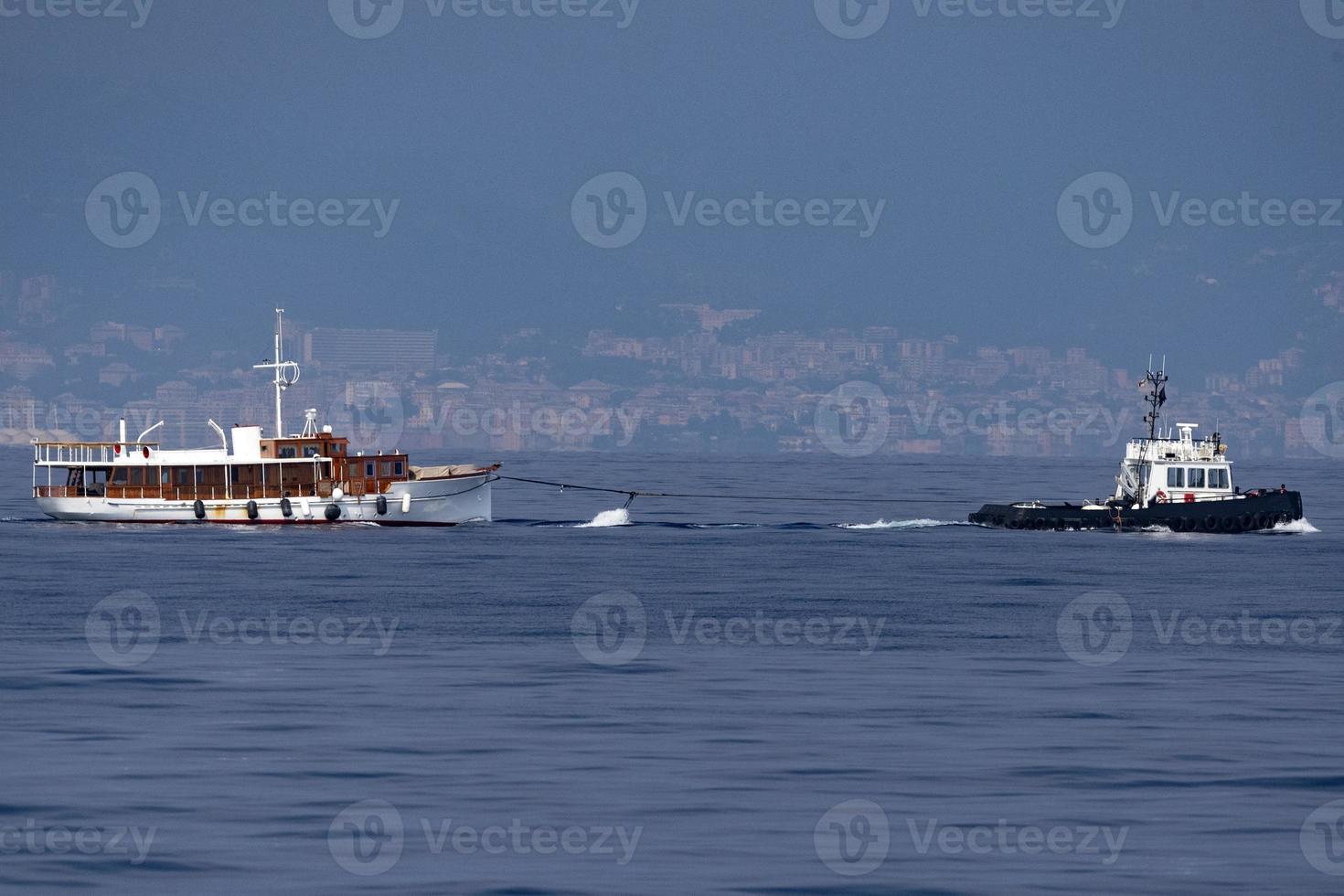 Schlepper, der ein kleines Bootsschiff schleppt foto