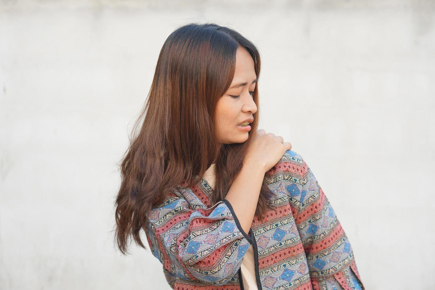 asiatische Frau mit Schulterschmerzen foto