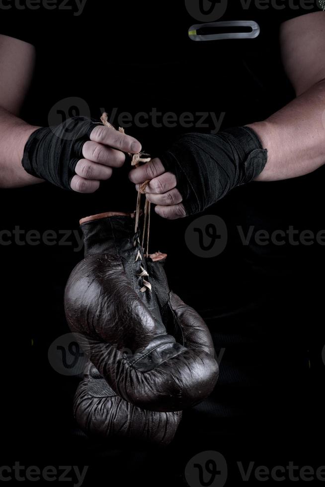 Paar sehr alte Boxsporthandschuhe in Männerhänden foto