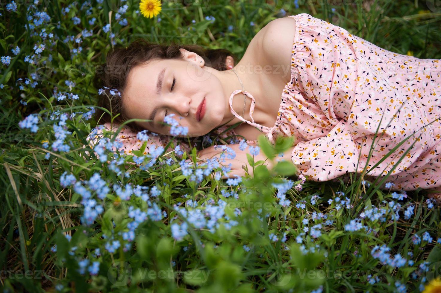 ein jung Mädchen Lügen im das Grün Gras mit ihr Augen geschlossen im ein Rosa Kleid foto