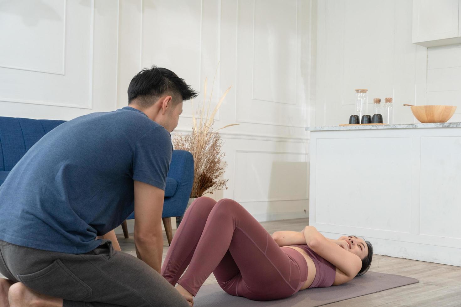 asiatisch Mann Hilfe und Unterstützung Freundin zu sitzen oben auf Yoga Matte foto