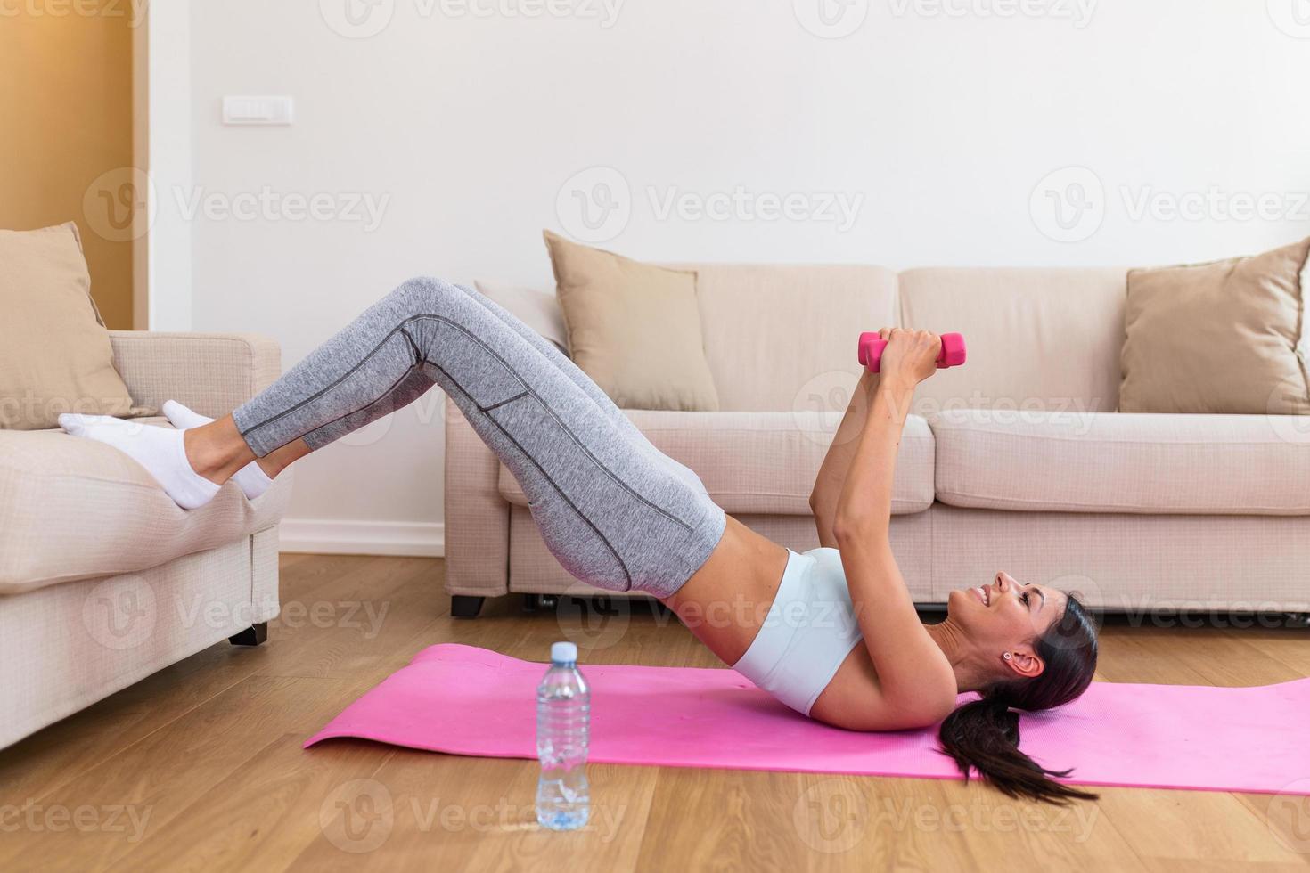 Fitness, trainieren, gesund Leben und Diät Konzept. jung Frau tun Gymnastik- Übungen beim heim. entschlossen Frau verlieren Gewicht beim Zuhause und ausüben mit Hanteln foto