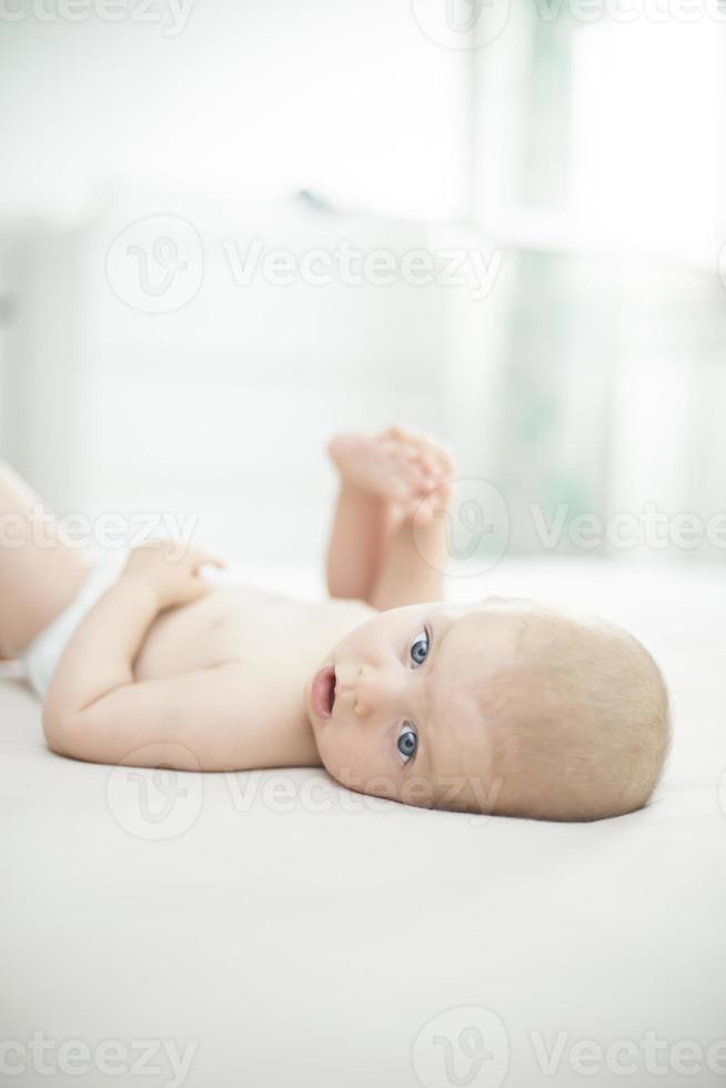 süßes Baby, das auf Bett liegt foto