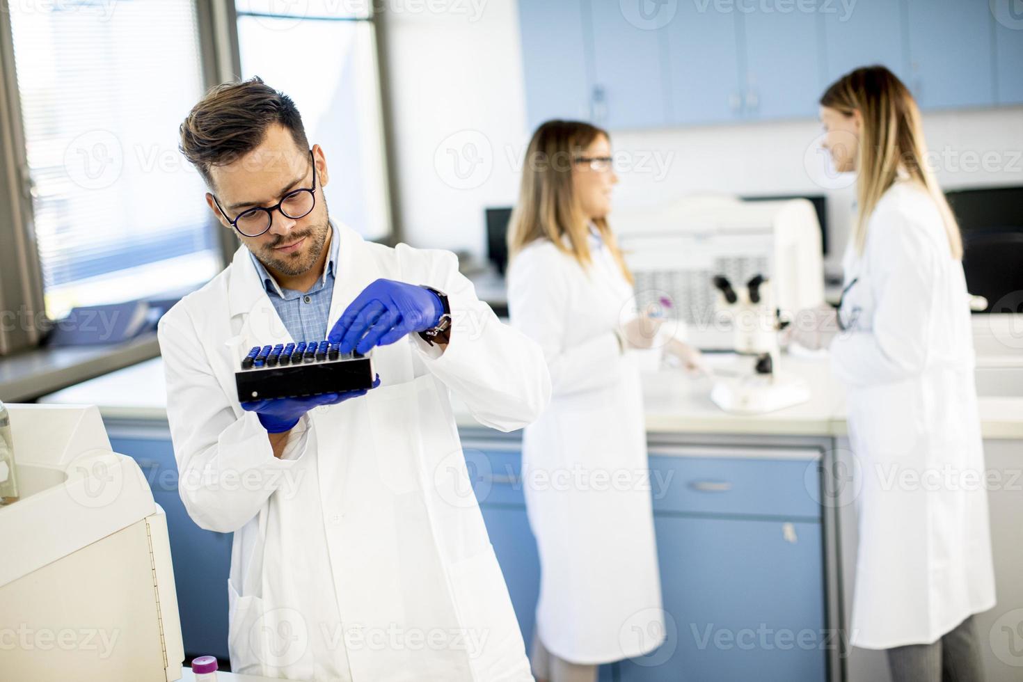 Forscher in Arbeitsschutzkleidung stehen im Labor und analysieren flüssige Proben foto