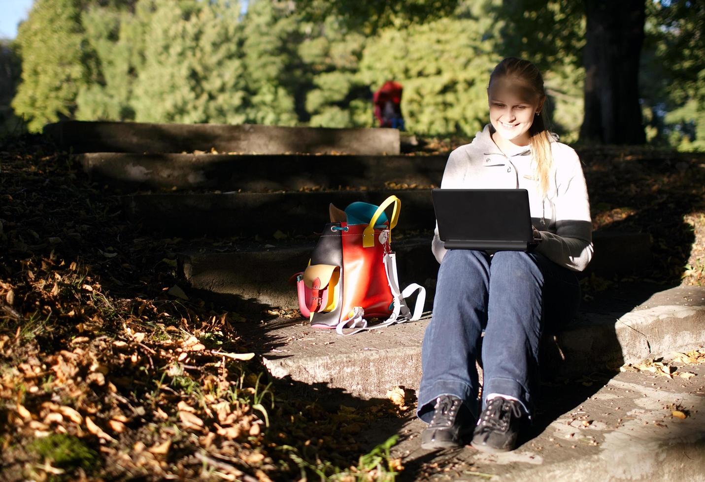 junge Frau, die draußen an einem Laptop arbeitet foto