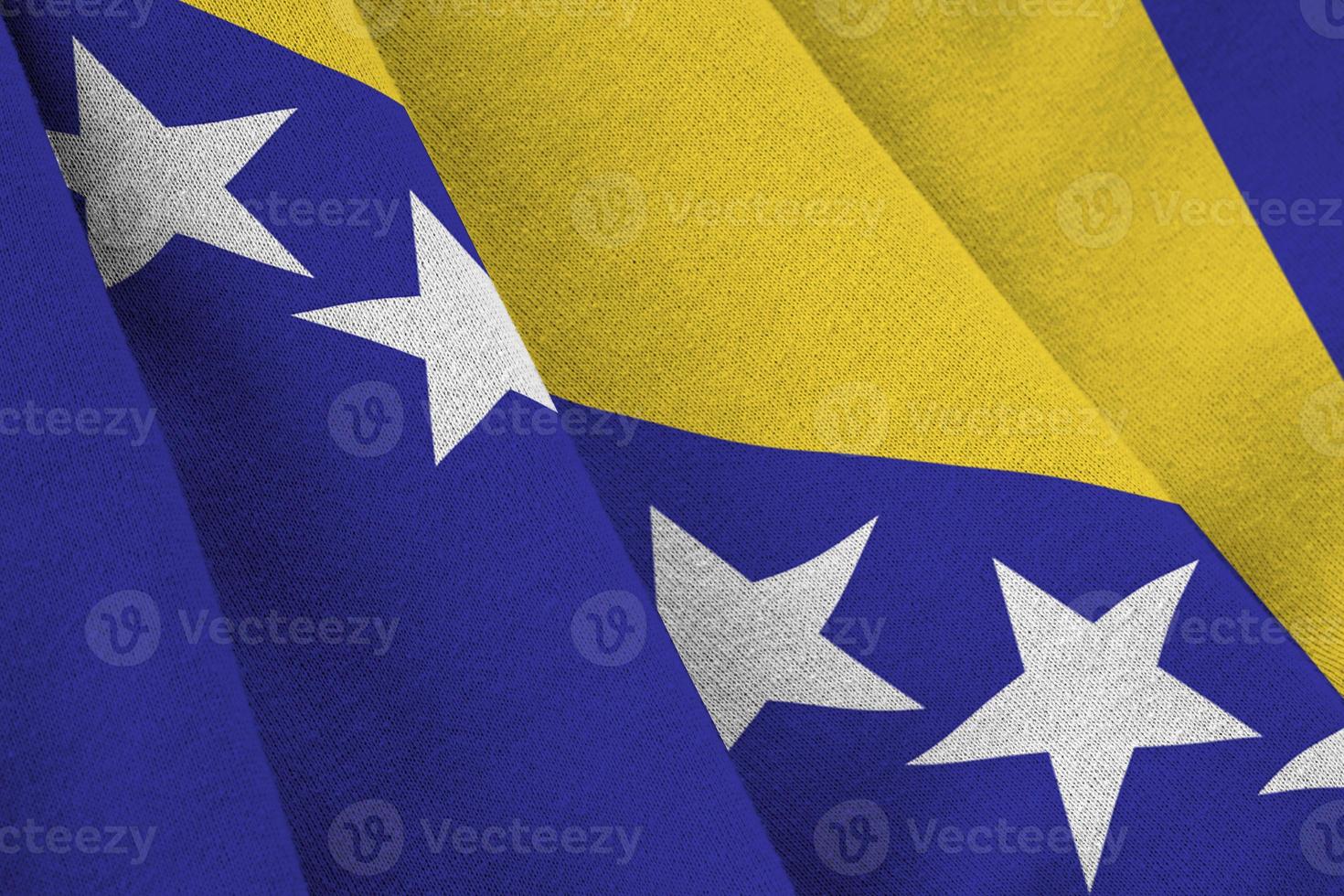 flagge von bosnien und herzegowina mit großen falten, die in der nähe unter dem studiolicht im innenbereich wehen. die offiziellen symbole und farben im banner foto