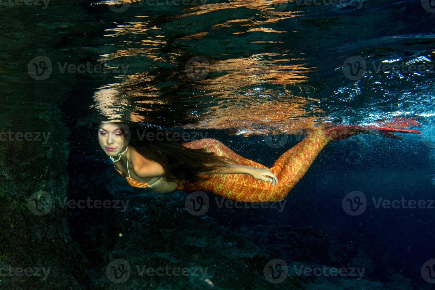 Meerjungfrau, die unter Wasser im tiefblauen Meer schwimmt foto