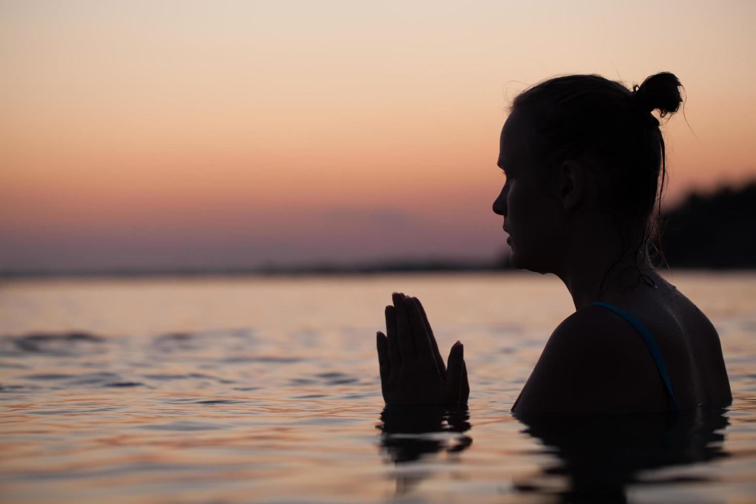 Silhouette einer Person im Gebet im Wasser foto