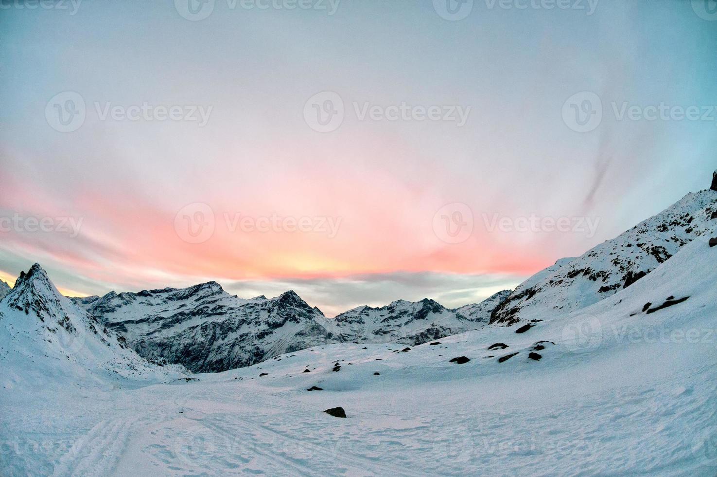 Hochgebirgssonnenuntergang auf den schneebedeckten Felsen foto