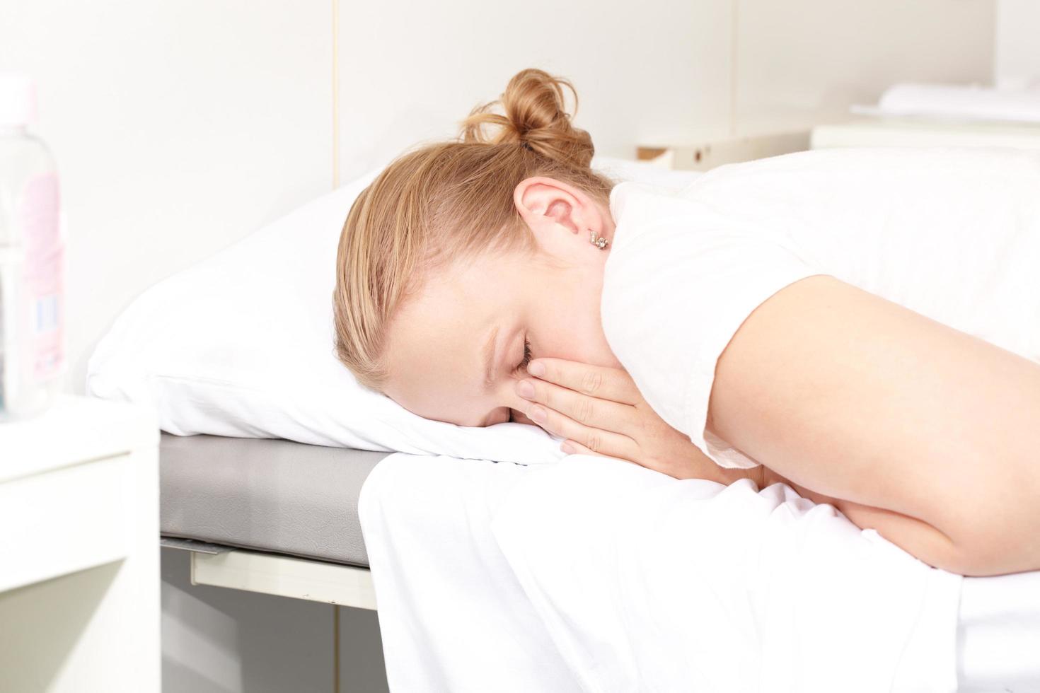 Frau, die auf einem Krankenhausbett liegt, das ihr Gesicht bedeckt foto