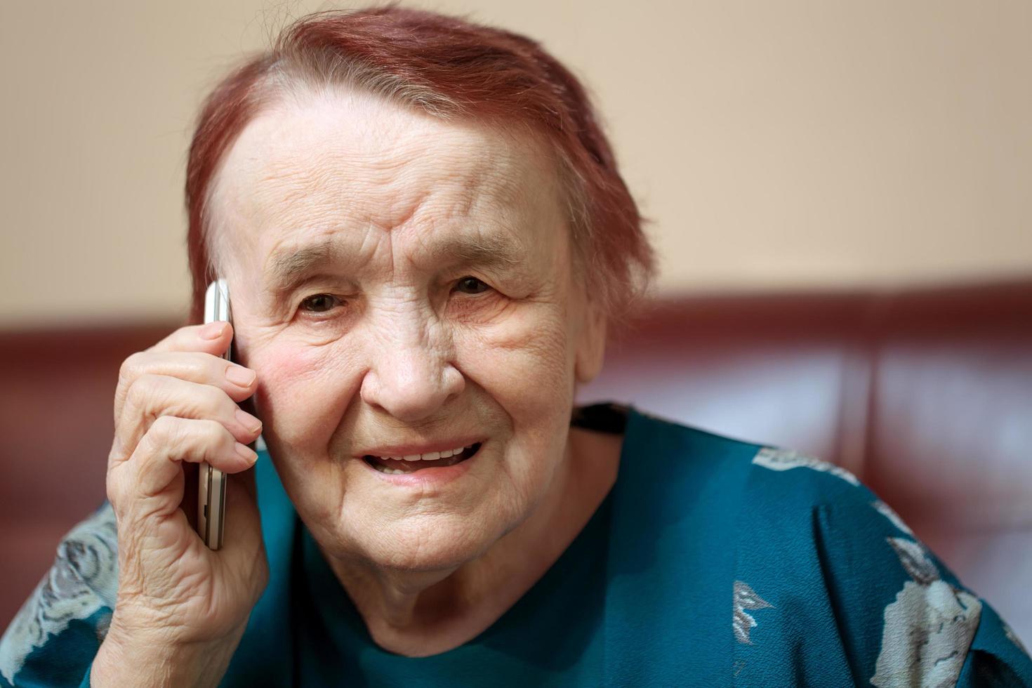 ältere Frau, die auf einem Mobiltelefon spricht foto