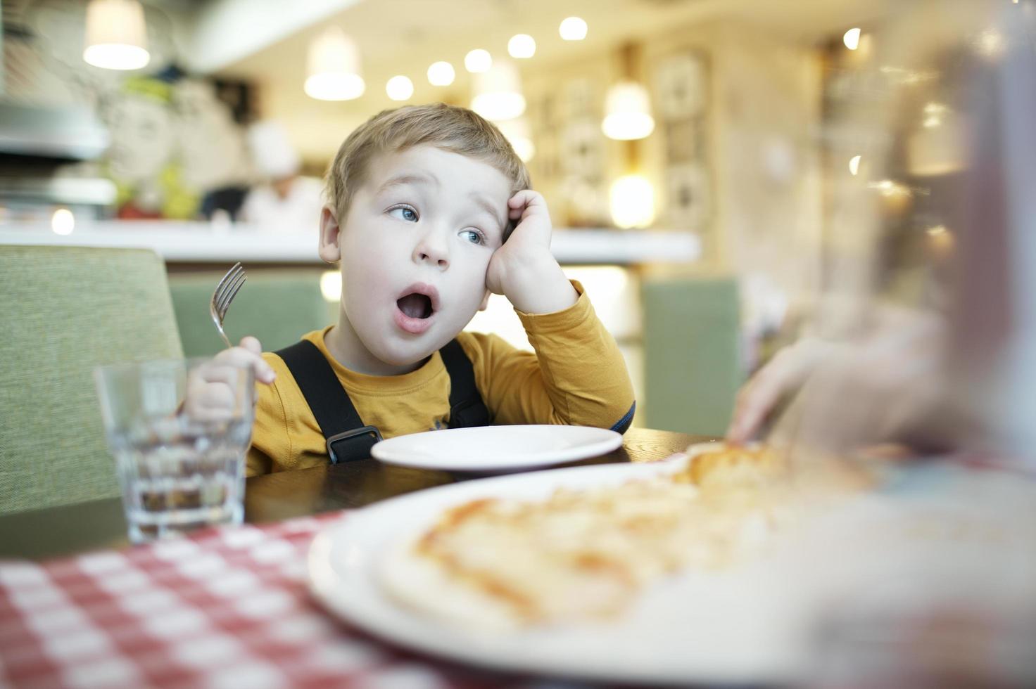 Junge, der an einem Restauranttisch gähnt foto