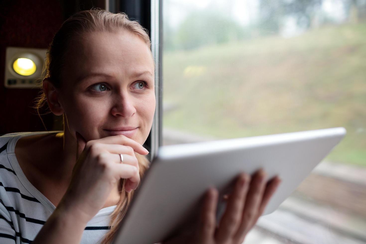 Frau hält eine Tablette in einem Zug foto