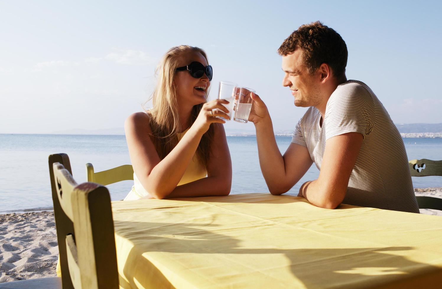 junges Paar, das Getränke am Meer genießt foto