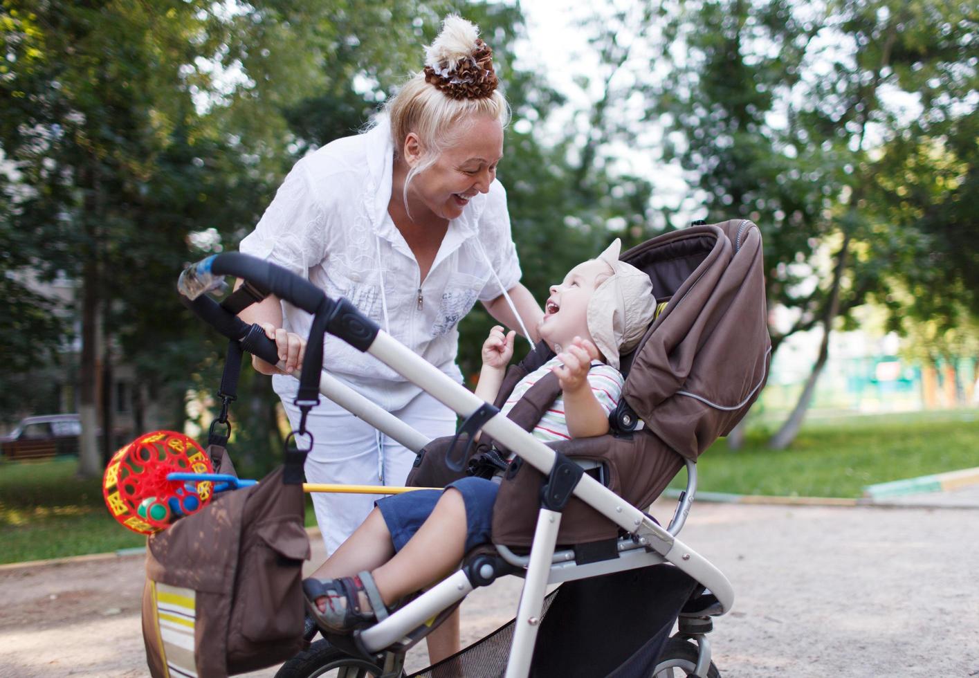 Großmutter spielt mit ihrem Enkel in einem Kinderwagen foto