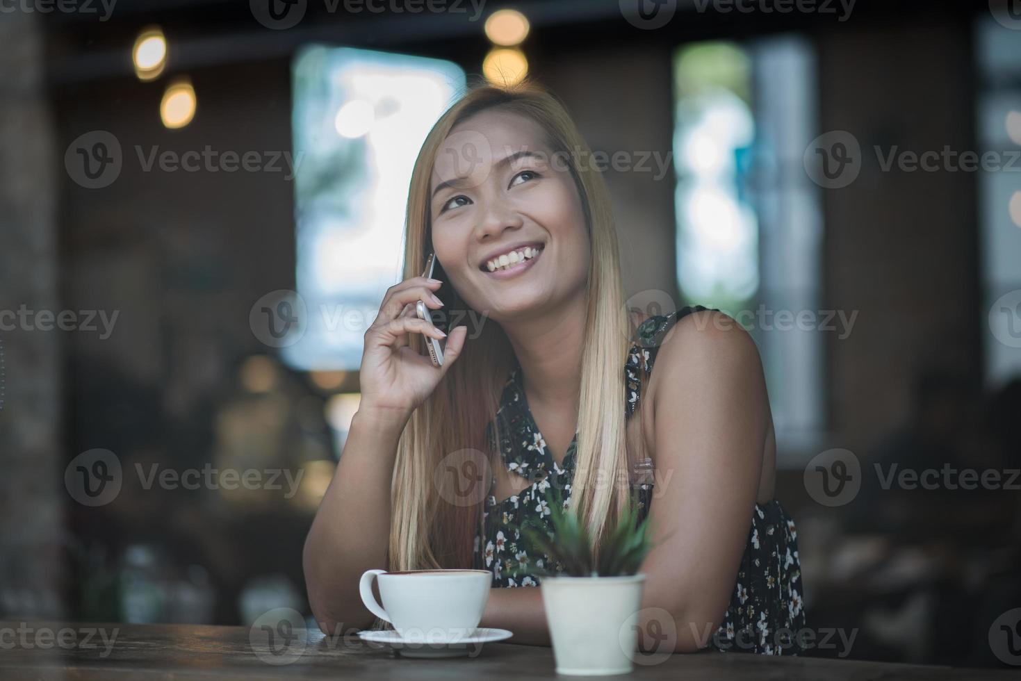 junge Frauen, die Smartphone am Fenstercafé benutzen und betrachten foto